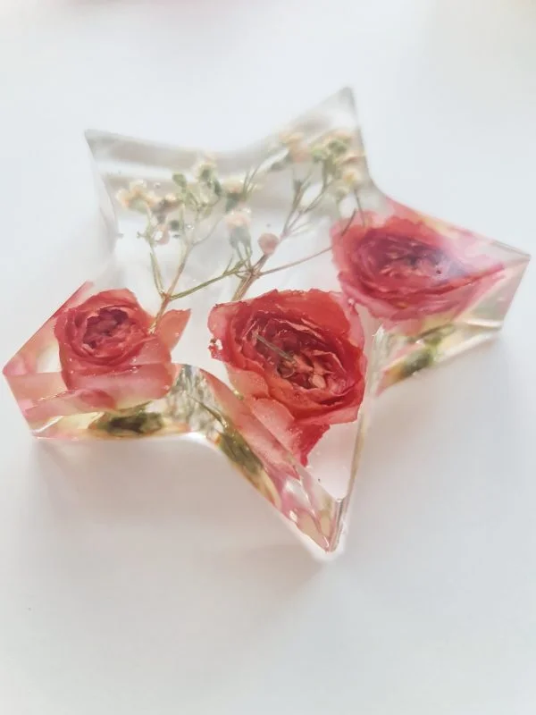crystal clear resin star with wedding flowers preserved within it. handcrafted in the UK