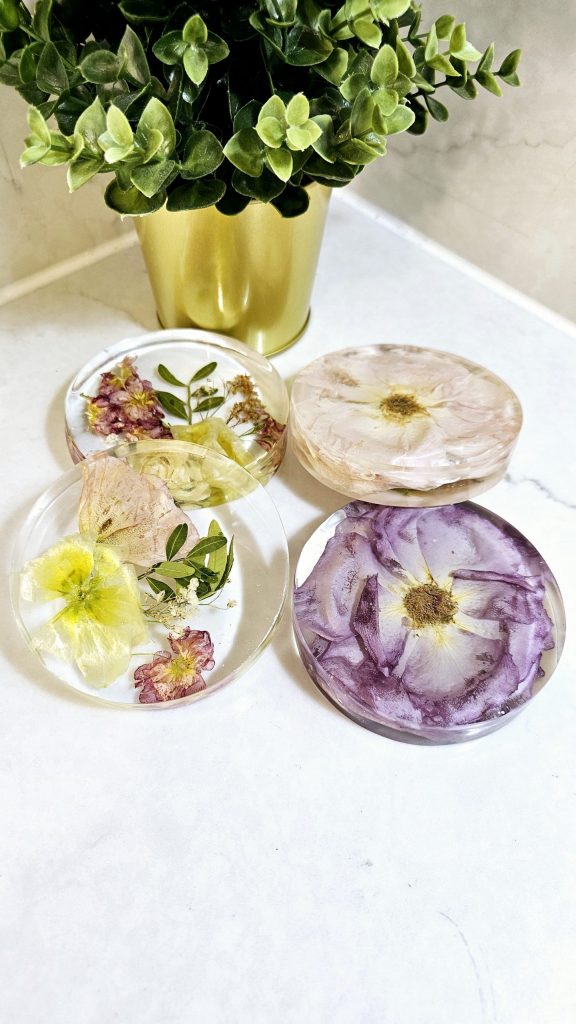 floral resin coasters made from preserved wedding flowers, featuring vibrant yellow, pink, and purple blooms, displayed next to a gold plant pot.
